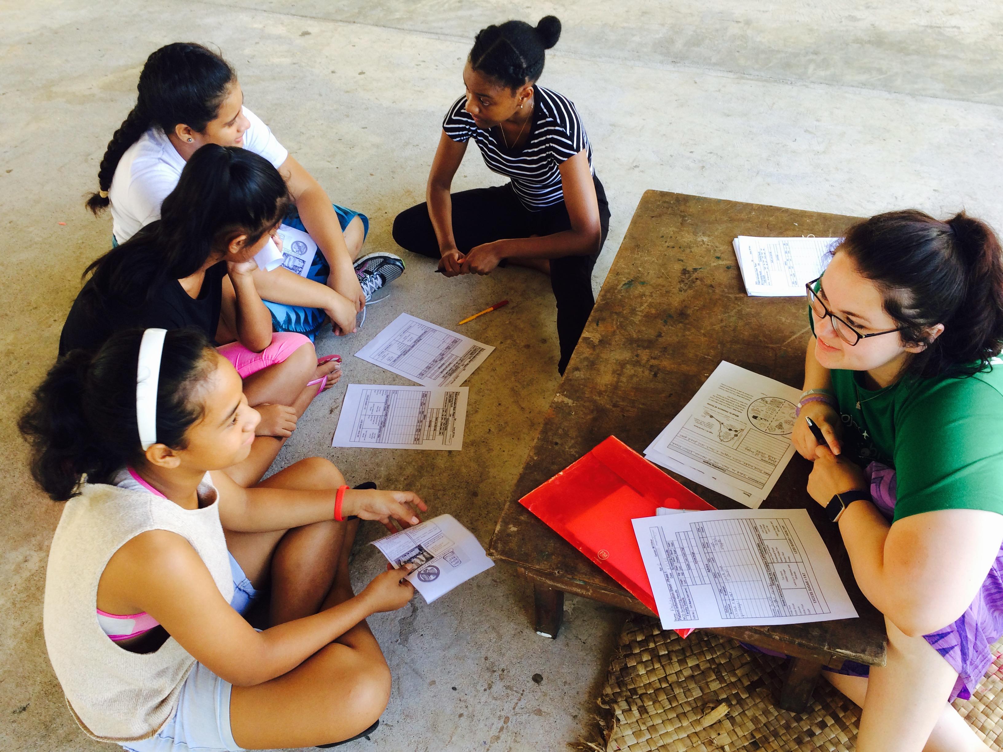 A Projects Abroad intern talks to local children for her nutrition work experience in Samoa. A student discusses healthy eating with local children during her Nutrition internship in Samoa.